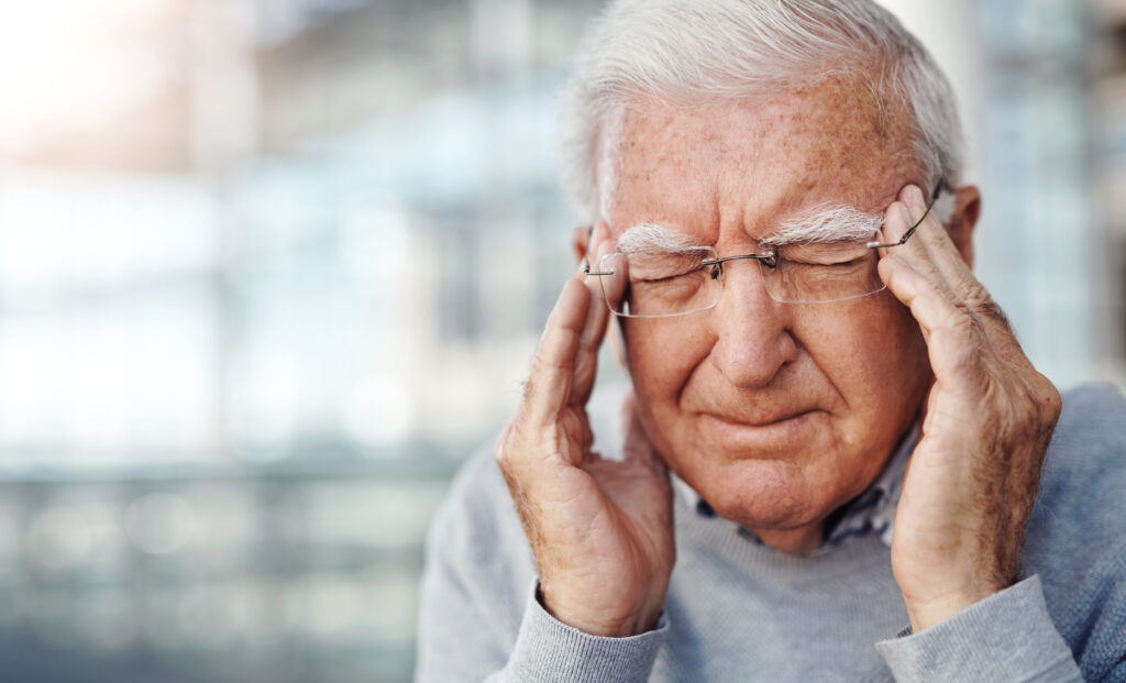 Alter Mann mit Kopfschmerzen an der Stirn
