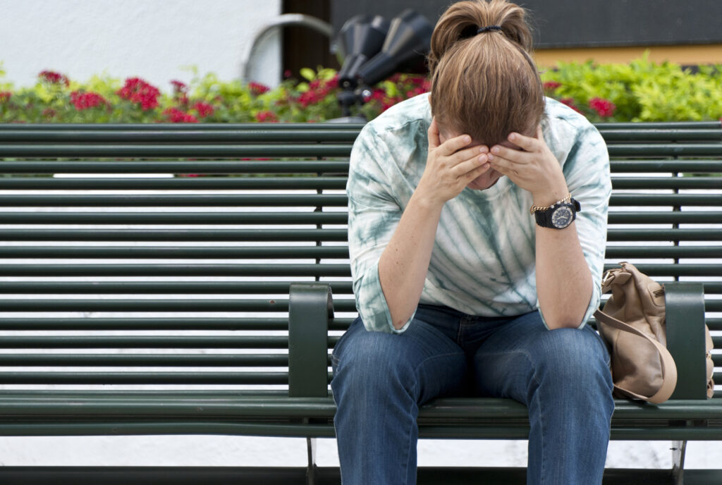 Jugendlicher sitzt auf der Bank und hat Kopfschmerzen