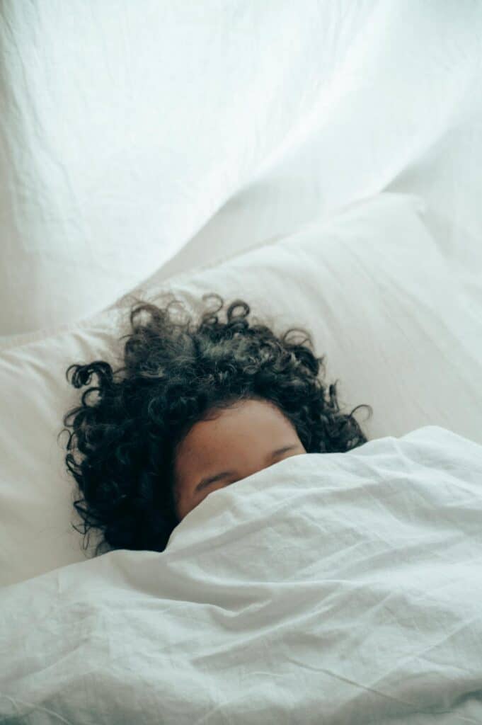 Frau im Bett hat Kopfschmerzen Nachts und verdeckt sich das Gesicht