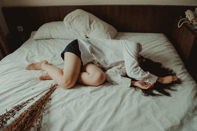 Frau hat Kopfschmerzen nach Impfung und liegt Nachts im Bett