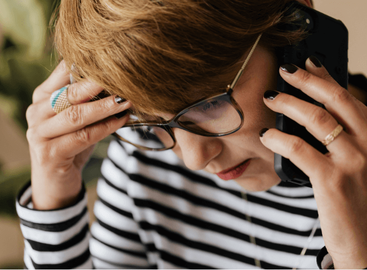 Frau in den Wechseljahren mit Migräne am Telefon